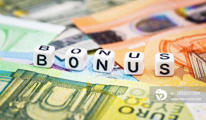 Small white beads with black letters BONUS on euro banknotes, closeup detail