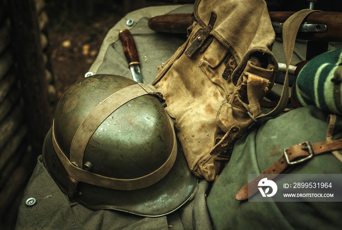 Military equipment of the Second World War. An iron helmet, a cloth bag, a backpack, and a knife. Photo in retro style.