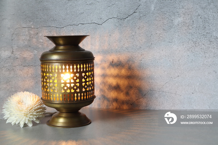 aroma essential oil brass and ceramic burner are put on the grey table with candles inside near a white flower on the background of crack cement wall in the luxurious day spa resort hotel Thailand