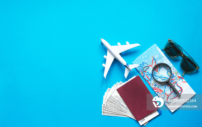 Travel accessories and objects on a blue background with a top view and copy space.Airplane and passport, money, map, ticket, sunglasses. Travel background for travel agency banner advertisement.