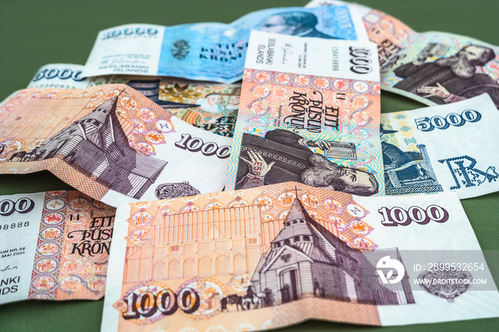 Pot of Icelandic krona banknotes laying on green carpet as a background