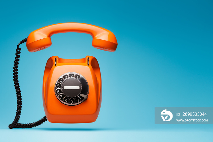 Old orange telephone rings with handset off.