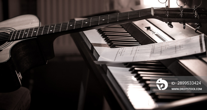 acoustic guitar stands on piano with notes, close-up, beautiful color background