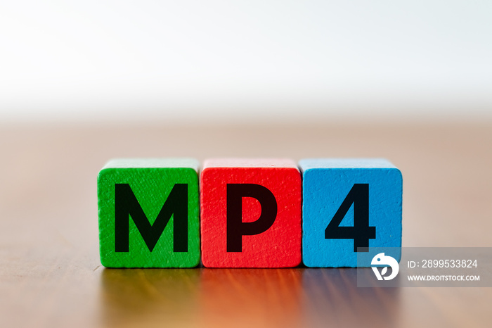 Three colorful wooden cubes with the lettering MP4 as a symbol for video files on a wooden table