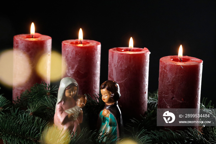 Natural advent wreath or crown with four burning red candles and christmas crib.  Christmas composition.  France.