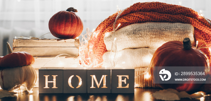 Background with warm sweaters and the inscription HOME. Pile of knitted clothes with leaves, pumpkins. Coziness. Autumn concept