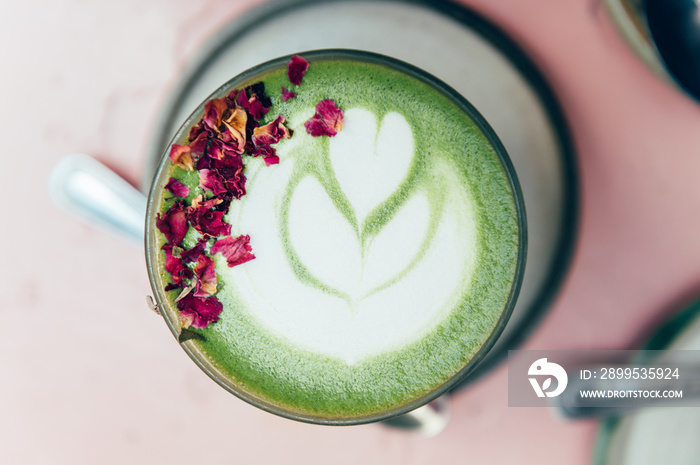 Glass of Super Latte such as Rose Matcha from Organic Japanese green tea powder infused with rose water. Flower petals and latter art on top