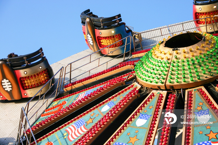 Fairground ride. A brightly decorated and illuminated American style Waltzer ride raising to a vertical position.