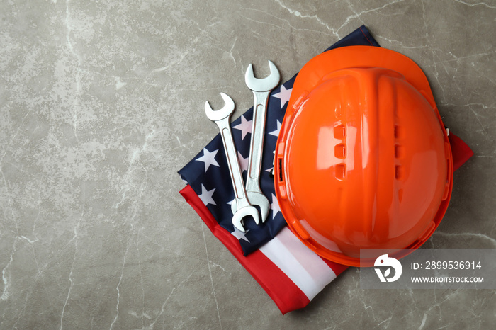 American flag with hard hat and wrenches on gray textured background