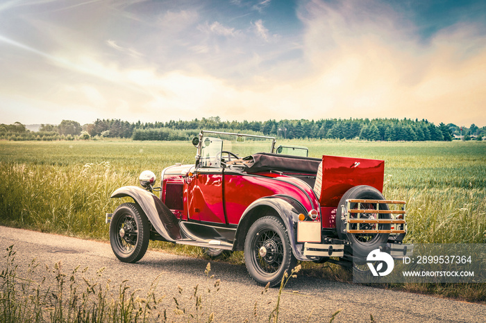 Antique red car on a road in a countryside landscape