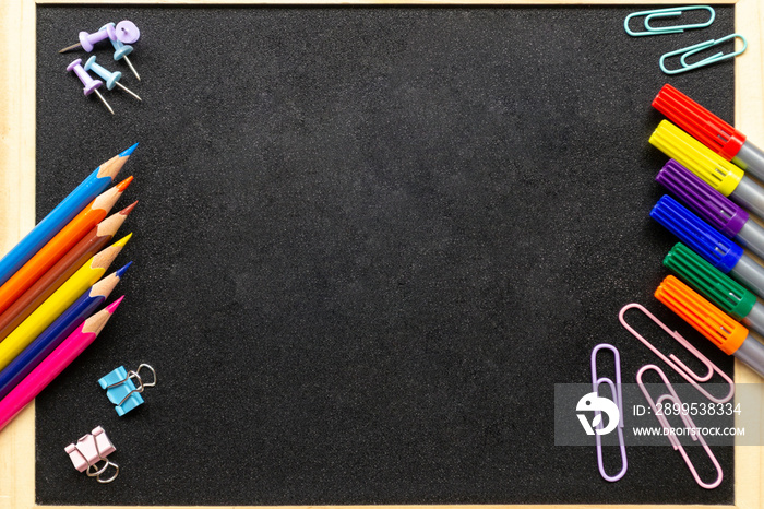 Various stationery: pencils, felt-tip pens, paper clips. School blackboard in wooden frame. Back to school and new academic year concept. Place for text, copy space