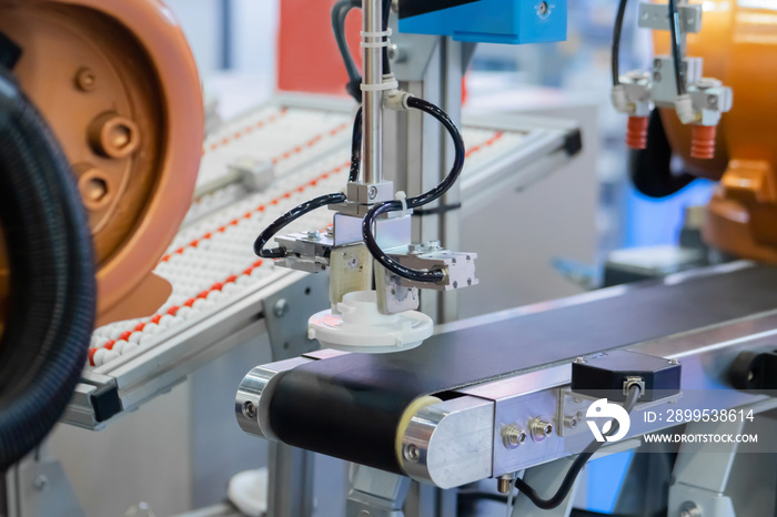 Pick and place robotic arm manipulator moving white plastic detail on conveyor belt at modern robot trade show, exhibition. Manufacturing, industrial, ai, engineering, automated technology concept