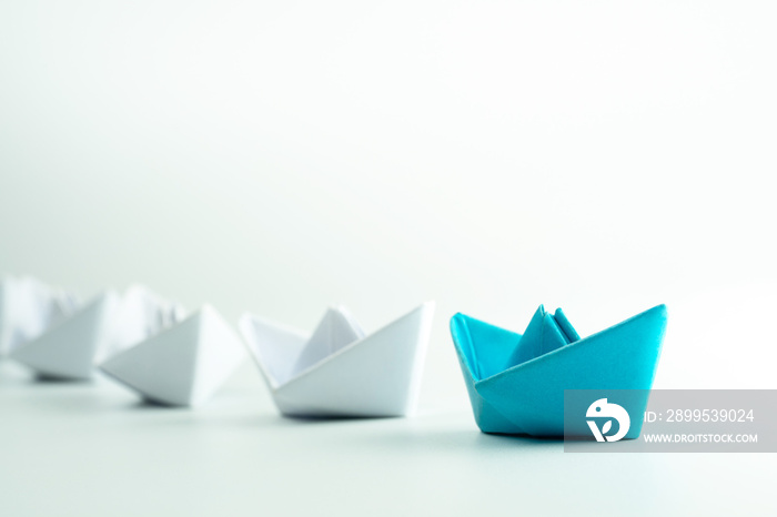 Leadership and Success concept with Blue paper ship leading a white paper ships.