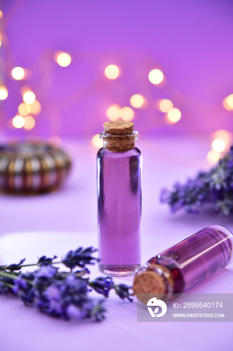 Lavender oil and lavender flowers on bokeh background.