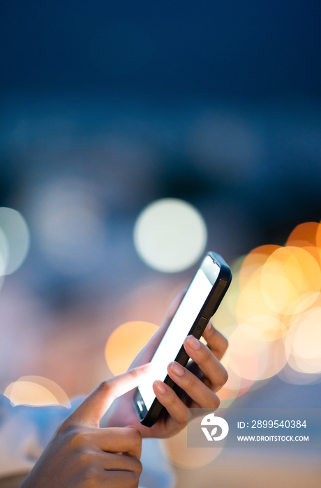 woman using mobile phone in the night city lights background.