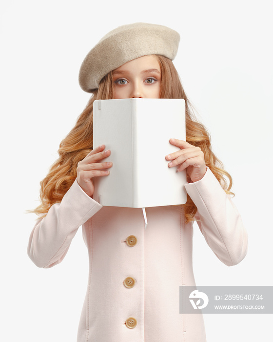 portrait of a stylish little girl in a pink coat, beret and glasses with a white book in her hands