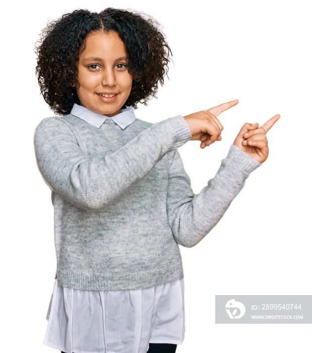 Young little girl with afro hair wearing casual clothes smiling and looking at the camera pointing with two hands and fingers to the side.