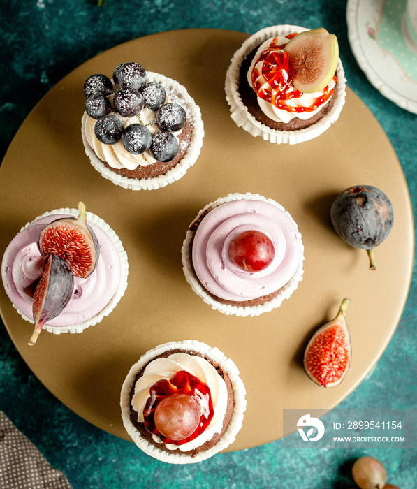 top view of chocolate cupcakes decorated with vanilla cream figs grapes and blueberries