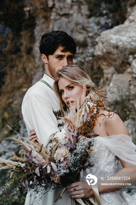 noise effect, selective focus: sincere emotions, passion and love of brides at a wedding photo shoot in the mountains against the backdrop of rocks and waterfall