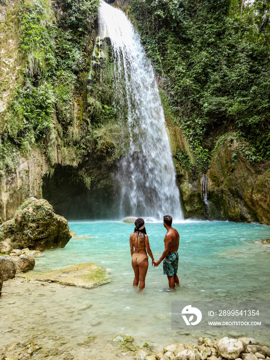 lovely couple alone in deep forest waterfall from mountain gorge at hidden tropical jungle Inambakan Falls in Cebu Island in Philippines