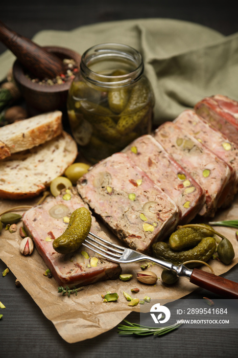 Sliced Traditional French terrine covered with bacon on dark wooden background