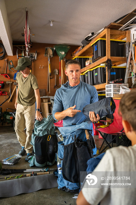 Air Force service member organizes gear with his sons before a backpacking trip.