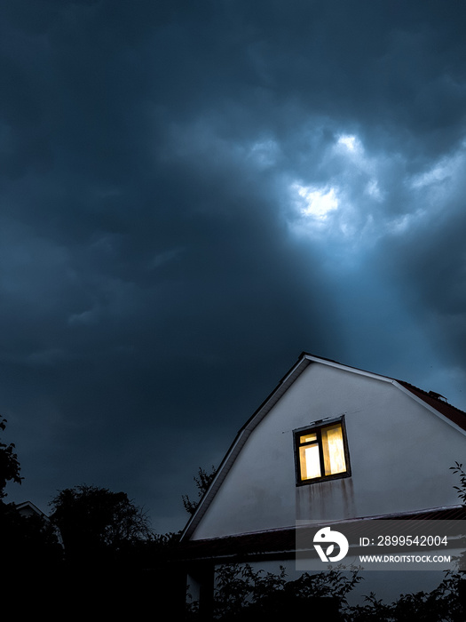 Lonely house under thunderclouds. The last ray of the sun breaks through the clouds. Clouds over the house before the storm