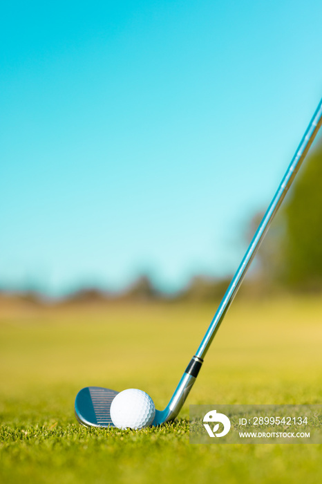 Close-up of golf ball with golf club on grassy land against clear blue sky during summer, copy space