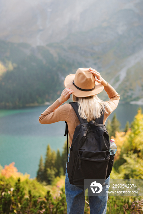 Woman traveler wearing hat and looking at amazing mountains and lake