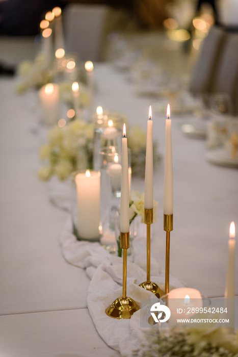 Table setting, serving closeup. Wedding setup detail. Banquet decoration in hall restaurant. Luxury reception. Festive table covered tablecloth, decorated composition flowers and candles in party area