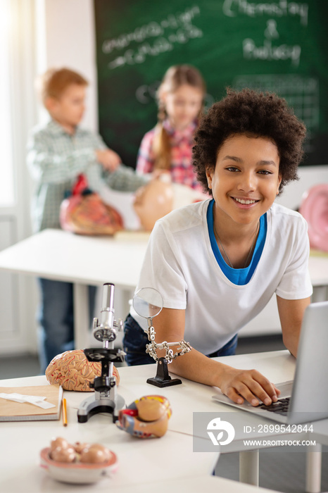 Interesting lessons. Cheerful happy boy smiling to you while enjoying the class