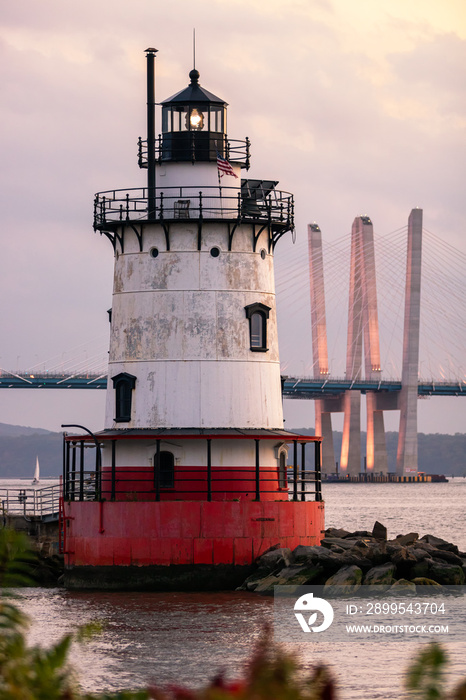 Caisson (sparkplug) style lighthouse under soft golden light with a bridge in the background. Tarrytown Light on the Hudson River in New York.