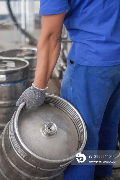 Man putting beer kegs on the production line in the factory