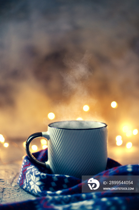 Winter coffee mug covered with wool scarf over bokeh lights