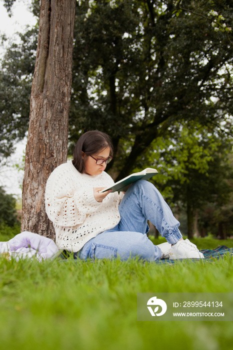 Curvy woman with Down syndrome reading in the park