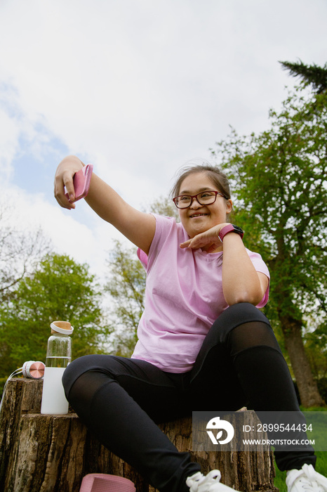 Young curvy girl with Down Syndrome taking selfie after workout