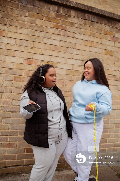 Two plus-sized women with Down Syndrome in workout clothes having fun and listening to music