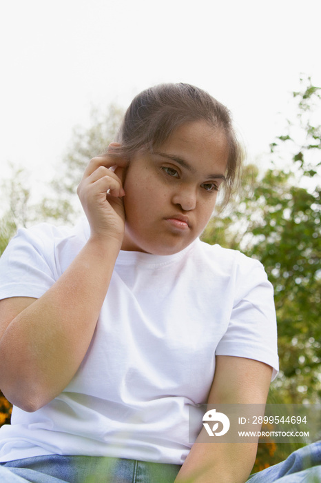 Young curvy woman with Down Syndrome listening to music