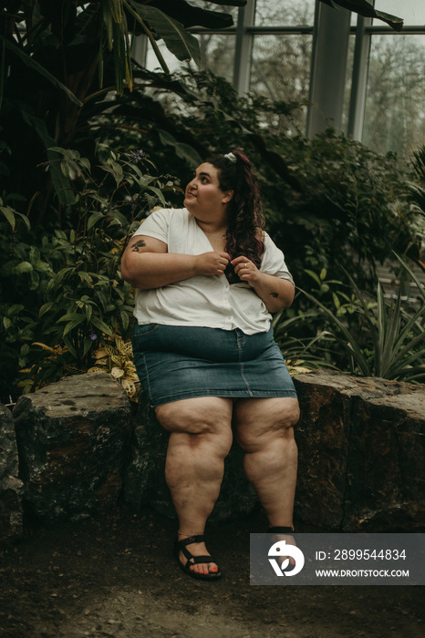 plus size woman sits surrounded by plants