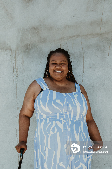 plus size woman smiles at camera standing against wall