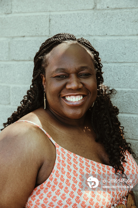 closeup of a plus size African American woman smiling against brick wall