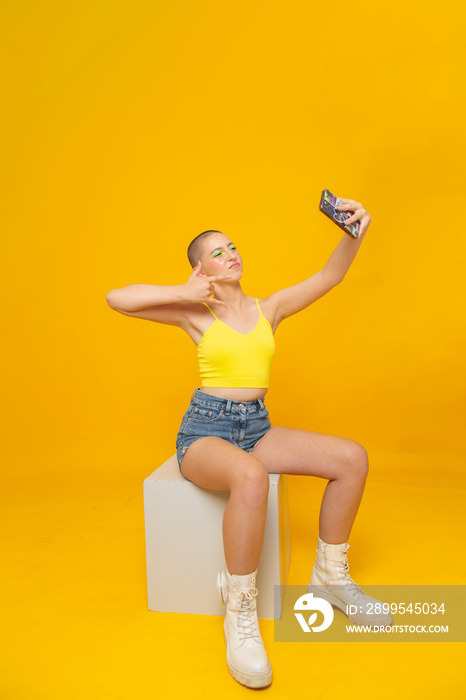 Studio shot of girl with neon colored make-up taking selfie