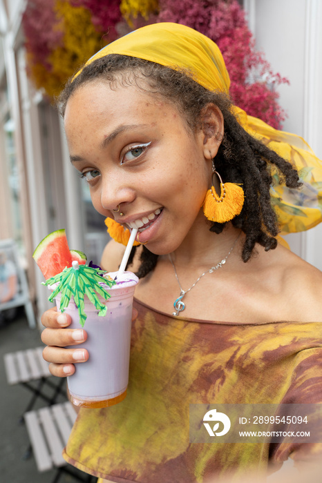 Portrait of young woman drinking smoothie in city