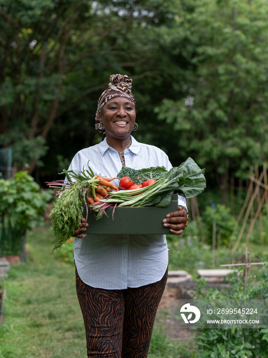 Smiling mature woman holding vegetables from garden