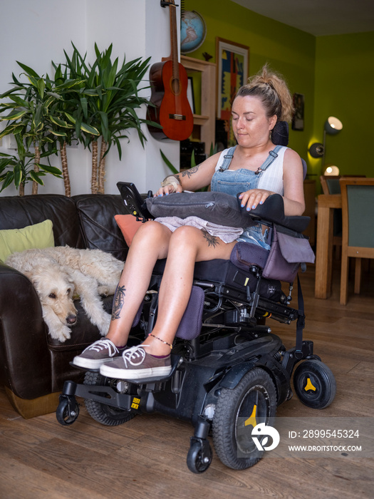 Woman in electric wheelchair with dog in living room