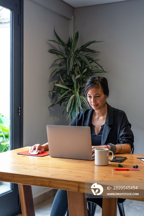 Young woman working online at home with laptop and documents