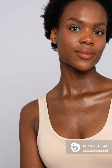 Studio portrait of smiling woman in cream colored tank top