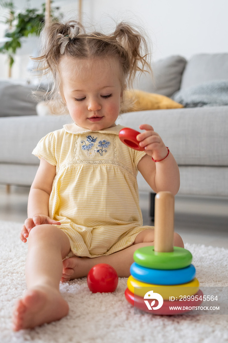 Child and play activities. Kid girl play colourful wooden pyramid in room.Baby building with interest. Educational games for development of children concept