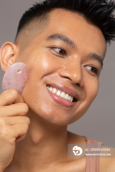 Close-up of smiling person using rose quartz guasha