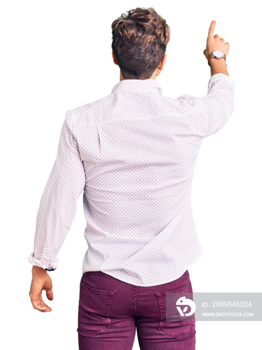 Young handsome man wearing business clothes and glasses posing backwards pointing ahead with finger hand